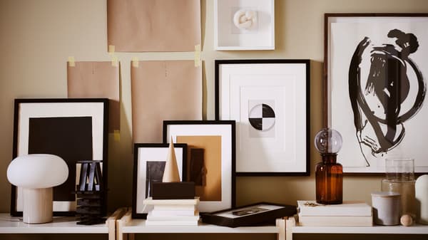 A picture wall in the making with pictures in RIBBA, KNOPPÄNG and LOMVIKEN frames, plus paper templates taped to the wall.