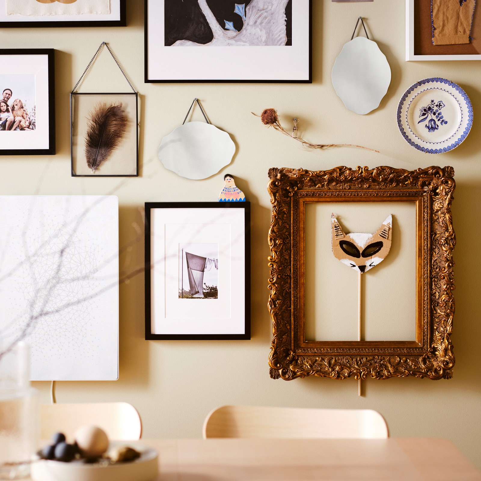 A picture wall over an ash RÖNNINGE table, with black RIBBA and LOMVIKEN frames plus other frames and decorative items.