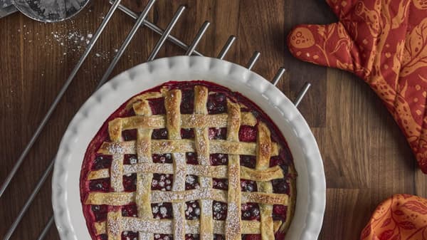 A pie with an oven mitt next to it with fall leaves on it.