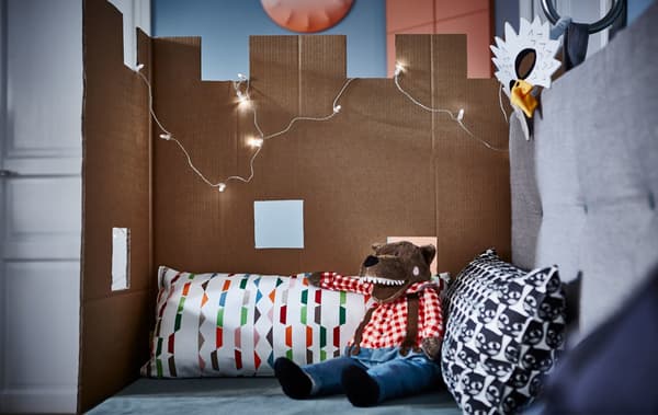 A piece of cardboard shaped like a castle attached to the side of a sofa with cushions
