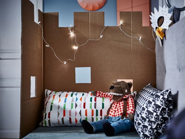 A piece of cardboard shaped like a castle attached to the side of a sofa with cushions.