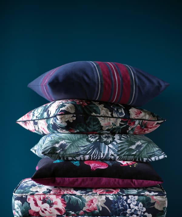 A pile of floral patterned cushions on a footstool.