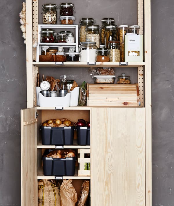 A pine pantry shelving unit organised with ingredients in glass and plastic containers and vegetable storage at the bottom.