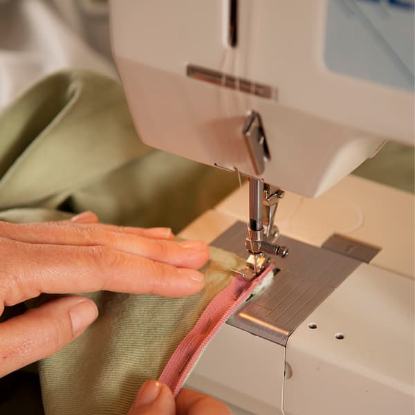A pink ribbon is sewn onto a green cover.
