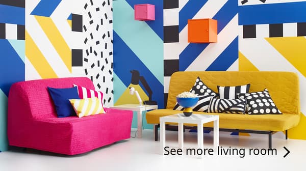 A pink sofa and a yellow sofa in a room with patterned walls. Text reads: See more living room >