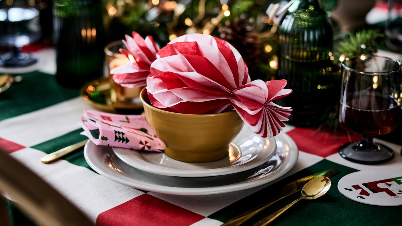 A placesetting with white plates and a gold bowl. There is a large candy decoration in the bowl.