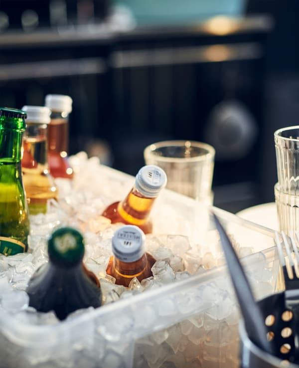 A plastic box with ice in and various bottles. 