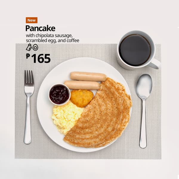 A plate of pancakes with chipolata sausage, scrambled eggs, hash brown, and jam, served with a cup of coffee. Price: ₱165.