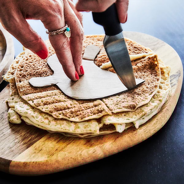 A plate of VINTERSAGA gingerbread on a plate with the red packaging behind it and a red and white striped fabric.