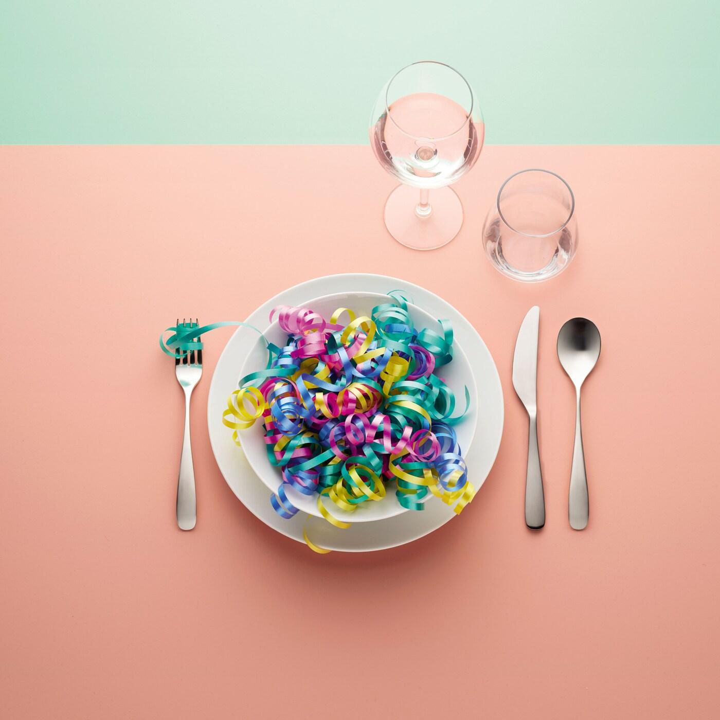 A plate on a with ribbon on it, some cutlery and glasses.