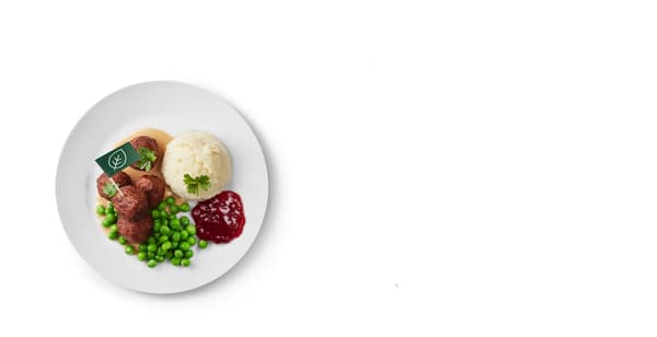 A plate with a child's portion of meatless meatballs, mashed potatoes, peas, cream sauce and cranberries.