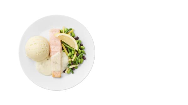 A plate with a portion of salmon fillet with bean mix, mashed potatoes, lemon-dill sauce.