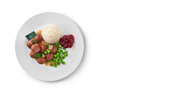 A plate with meatless meatballs, mashed potatoes, peas, cranberries and cream sauce.