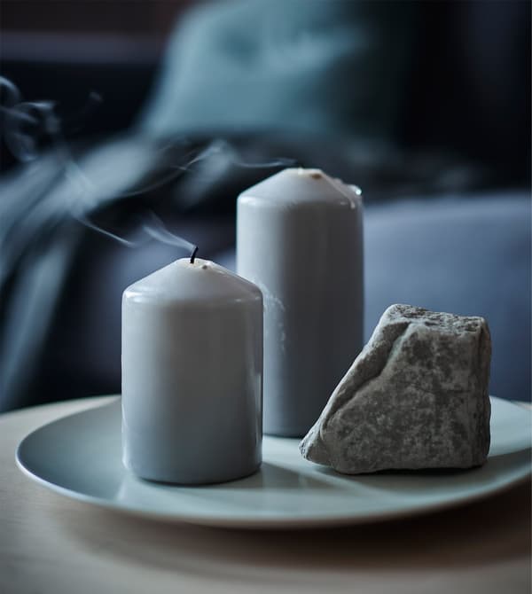 A plate with two block candles and a rock.
