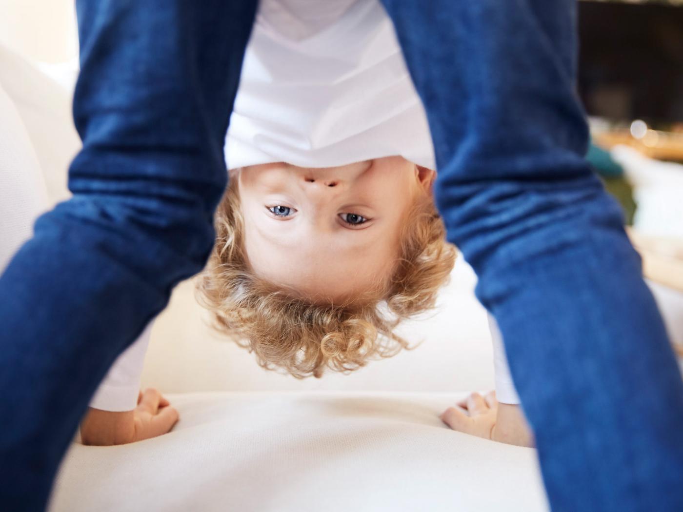 A playful boy stands on his hands while looking at the camera upside down and through his legs.