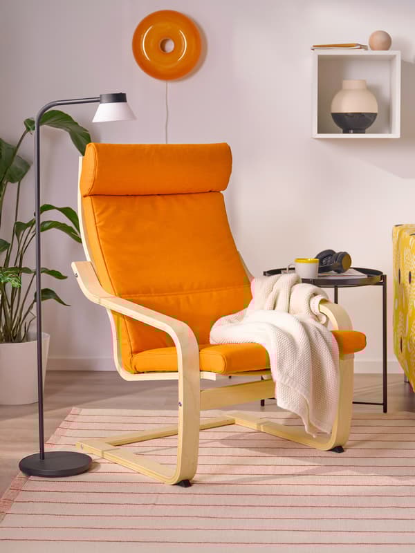 A POÄNG armchair with knisa bright orange armchair cushion in a living room setting.
