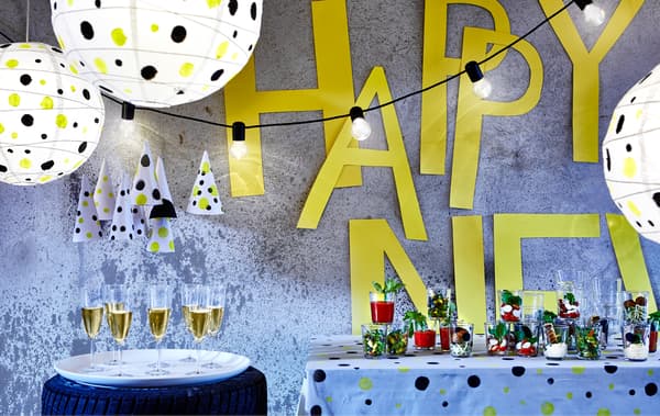 A polka-dot themed room decorated for a New Year party with food on a table, drinks in glasses and lighting decorations.