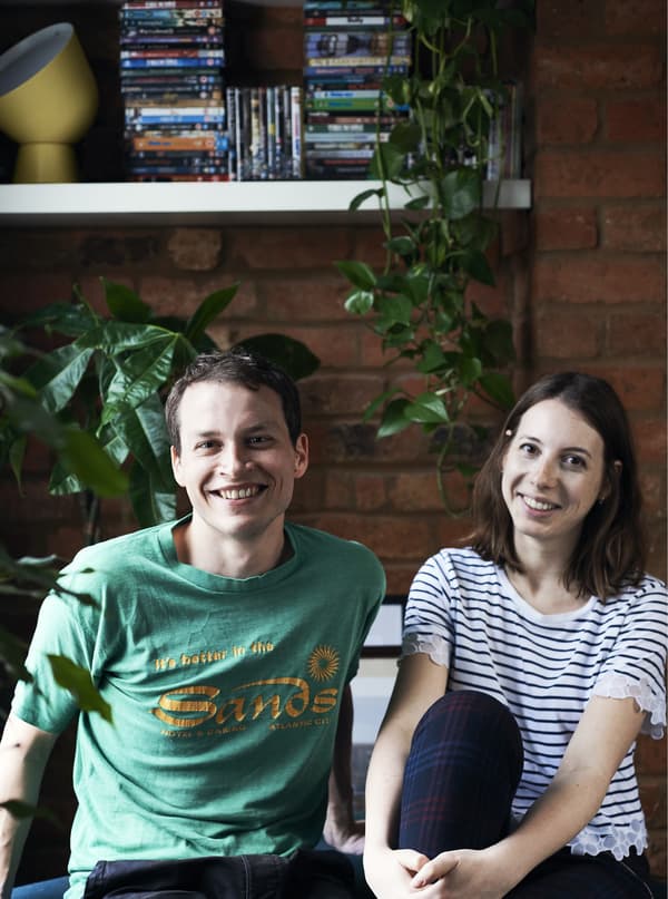 A portrait of a man and a woman in front of some green plants and a shelf.