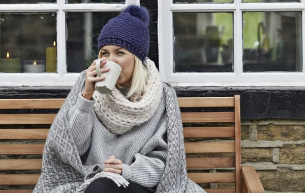 A portrait of Amanda outside her cottage, drinking coffee.