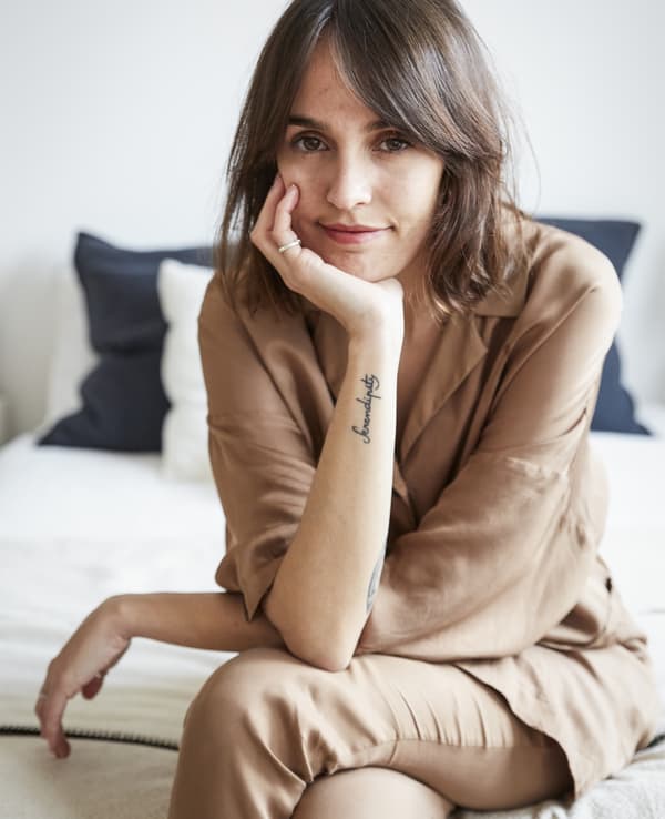 A portrait of Carolina sitting on her bed.