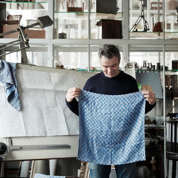 A portrait of Dutch designer Piet Hein Eik, pictured with a blue fabric sample from the IKEA INDUSTRIELL collection.