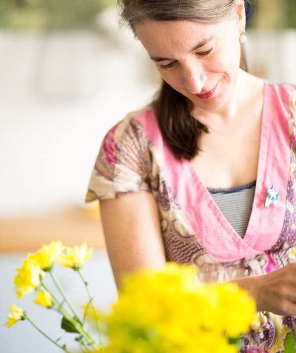 A portrait of Edna arranging yellow flowers.