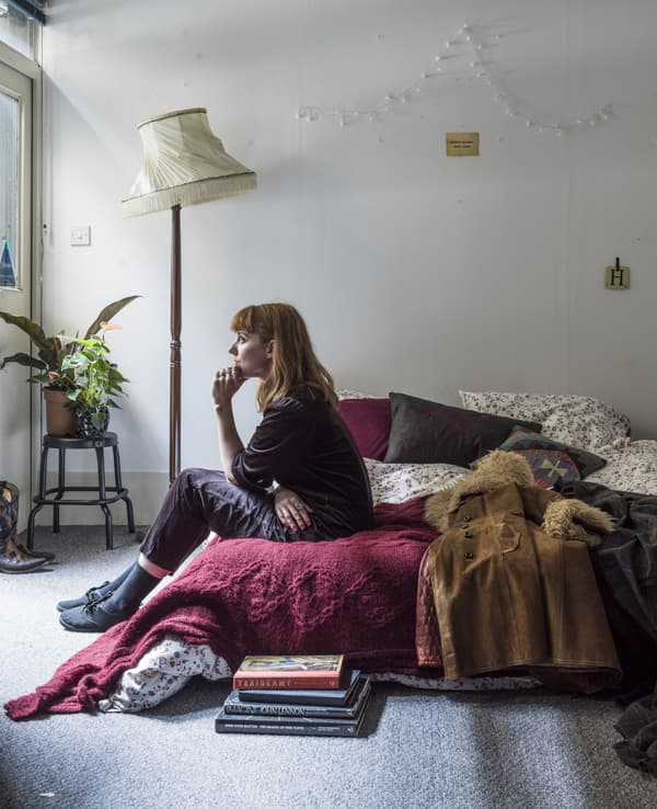 A portrait of Hannah sitting on her bed.