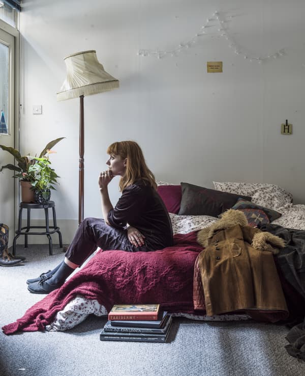 A portrait of Hannah sitting on her bed.