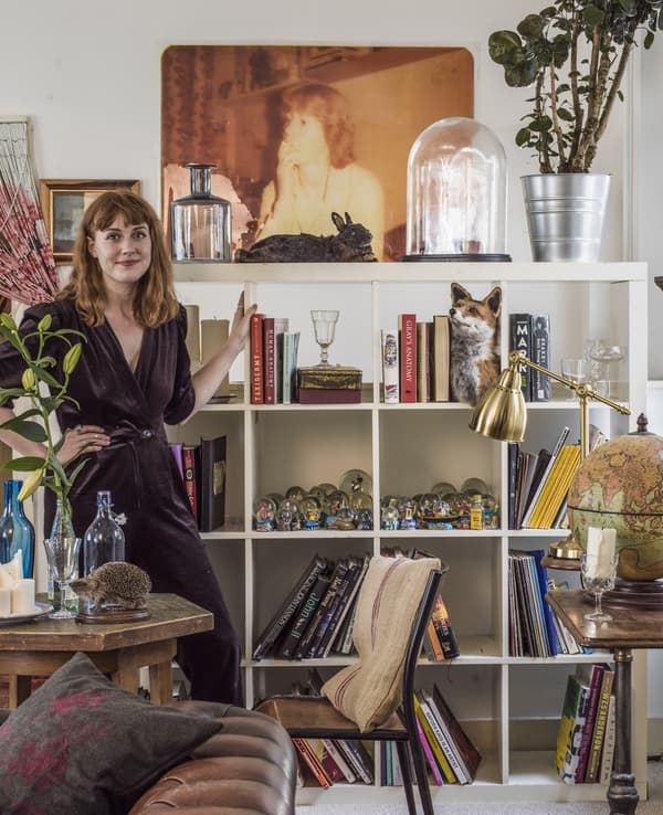 A portrait of Hannah standing by her open shelving.