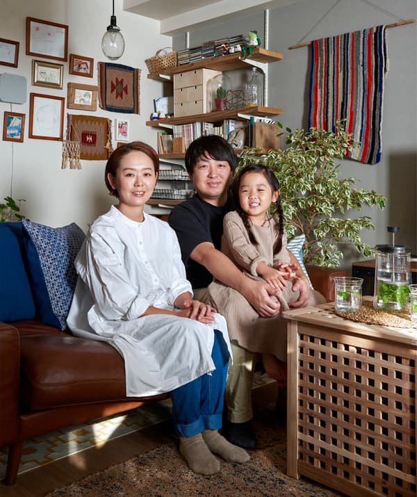 A portrait of Mieko, Kenta and their daughter sitting on the sofa.