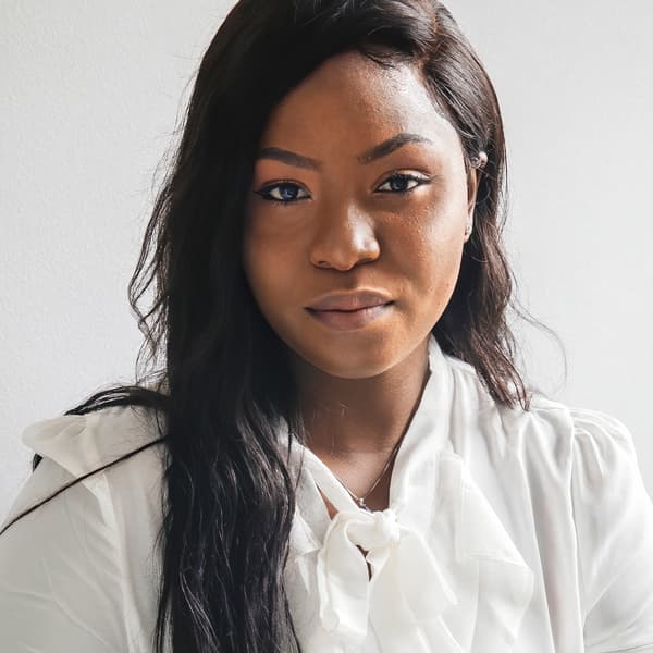 A portrait of Precious, a Nigerian refugee and IKEA Canada co-worker, wearing a white shirt against a white background.
