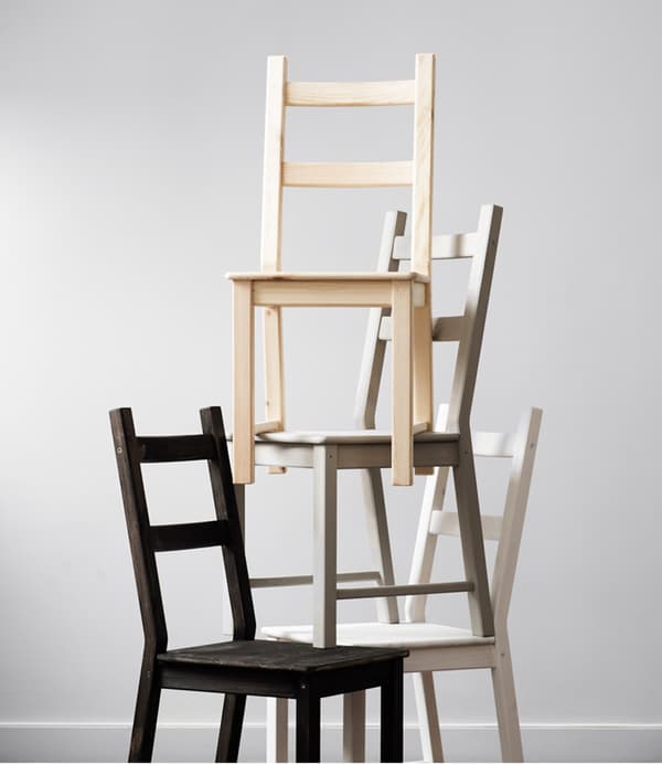 A pyramid of IKEA IVAR chairs, each varnished or stained a different colour.
