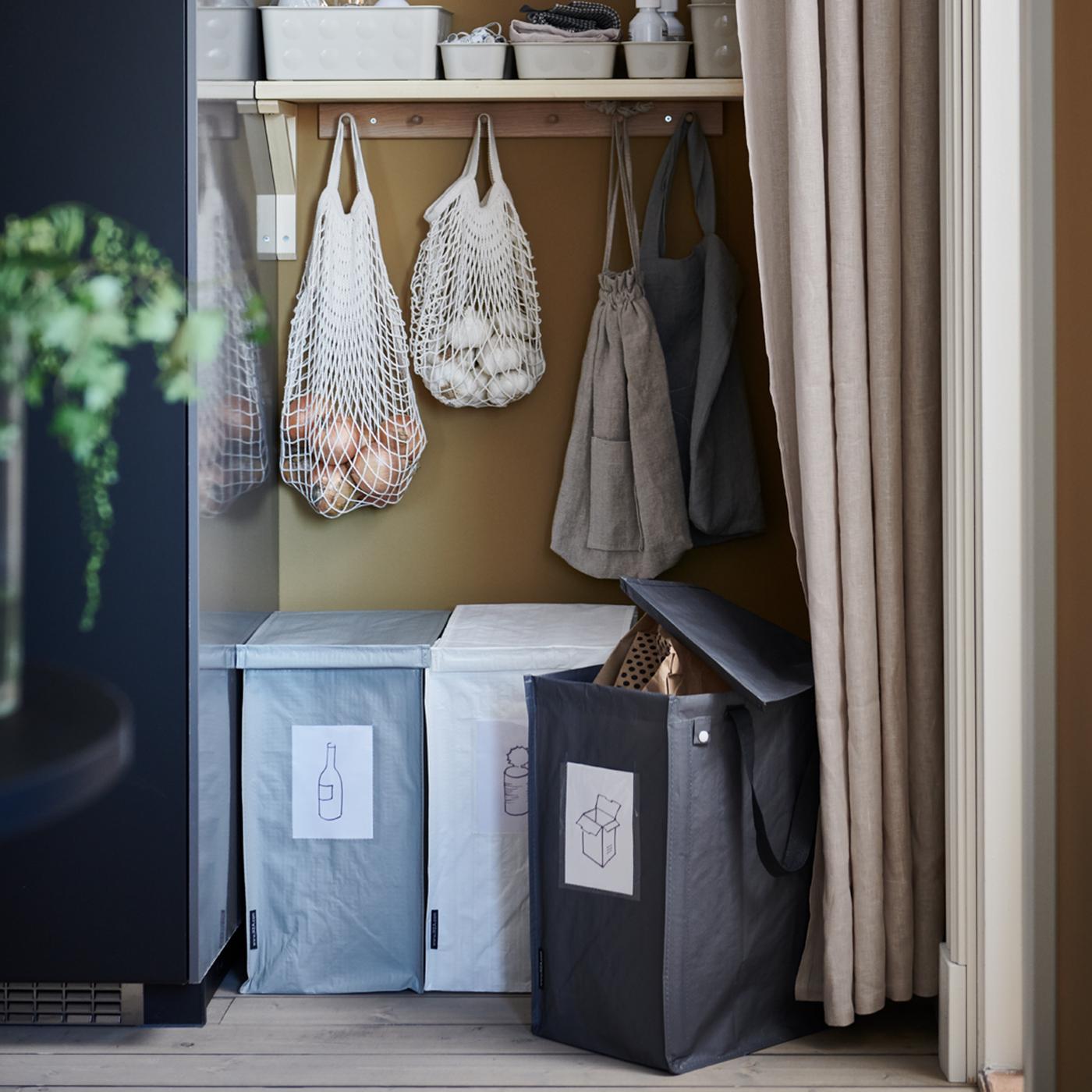 A recycling station with three DIMPA waste-sorting bags, a shelf and KUNGSFORS net bags placed in a recess behind a curtain.