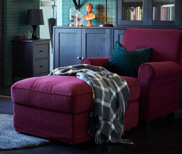 A red chaise longue with a blanked draped over it.
