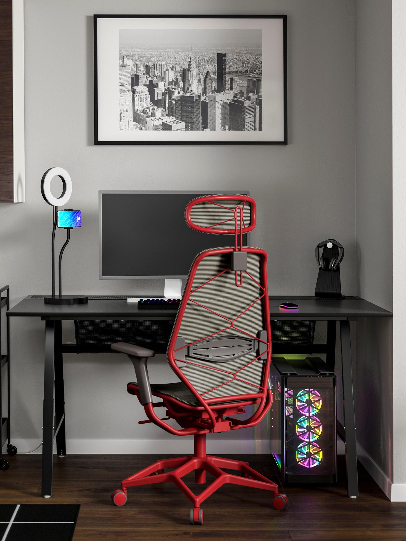 A red IKEA STYRSPEL gaming chair in front of a black game desk.