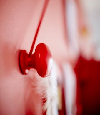 A red knob on a red wall that has a red ribbon attached to it