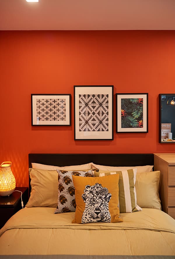 A red room featuring a bed with picture frames hung on top.