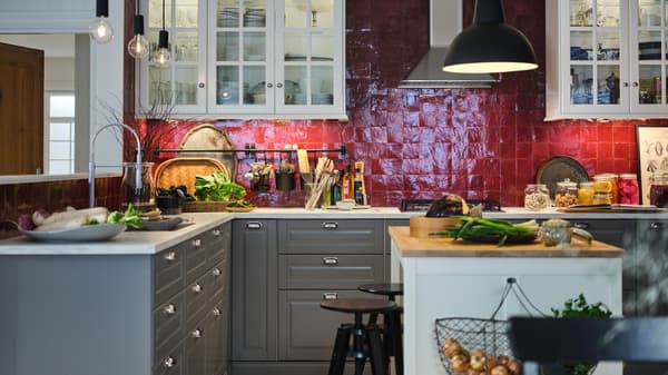 A red-tiled kitchen with white wall cabinets, grey base cabinets, white marble effect worktop and an island with a worktop.
