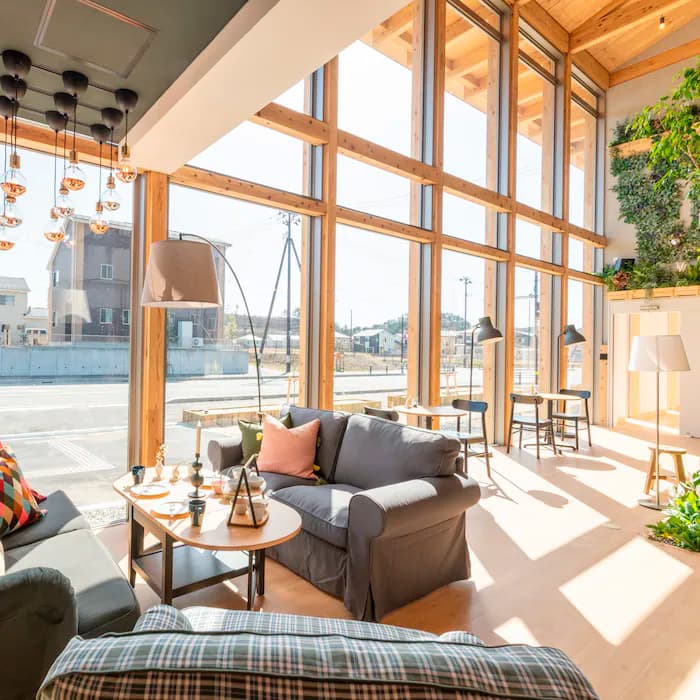 A relaxation area in an office, with two grey sofas, a window, plants and a lot of light.