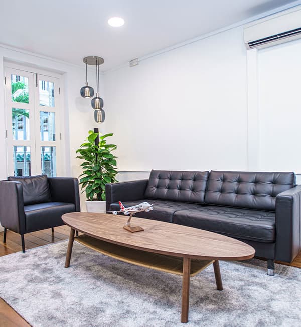 A relaxing area with a sofa, sofa chair and oval coffee table placed on top of a grey carpet.