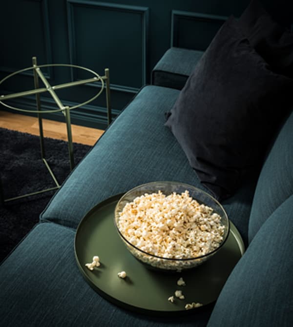 A removable tray from the side table holds a bowl of popcorn on the sofa.