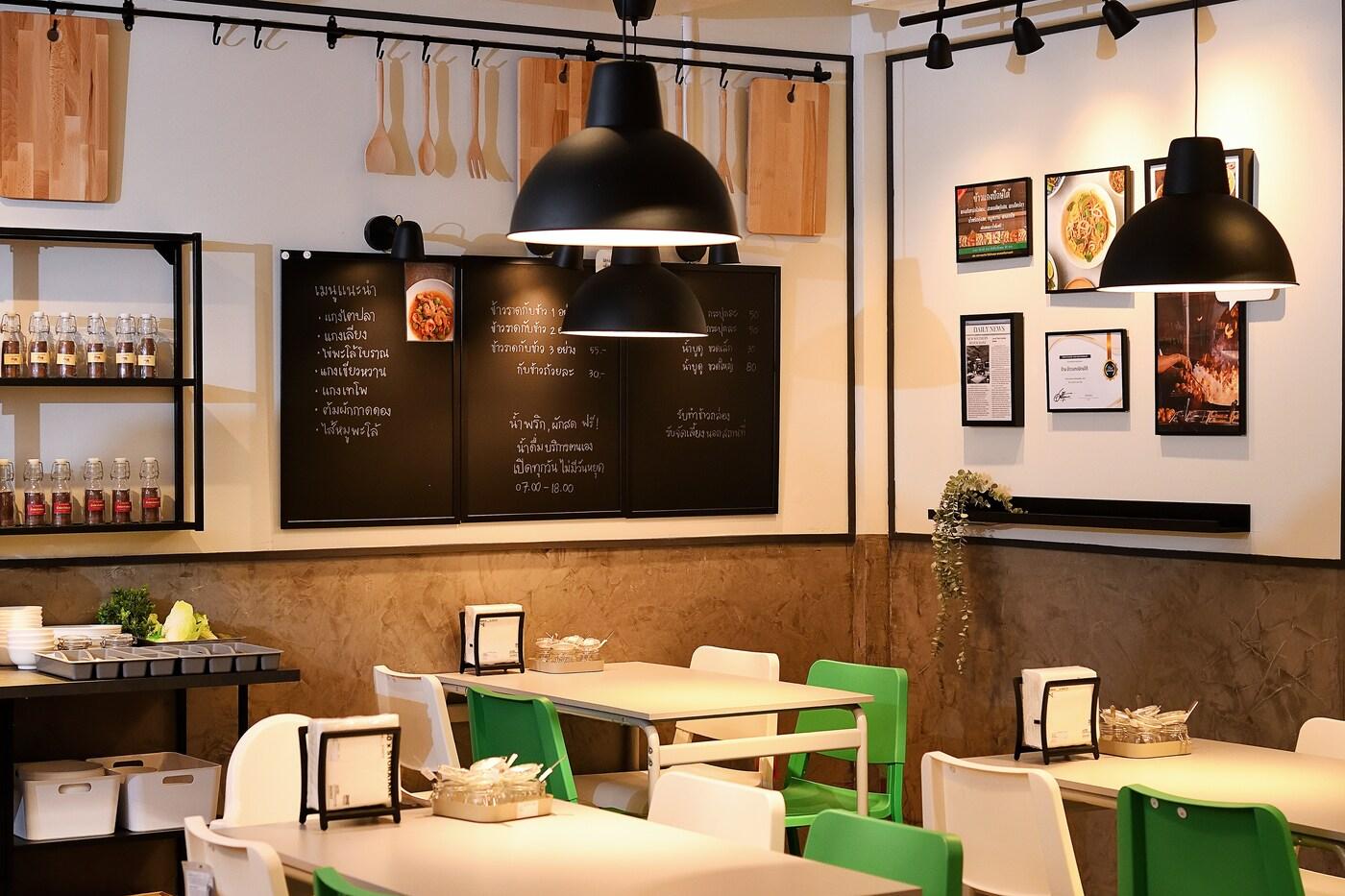 A restaurant space including white tables and chairs, display shelves and a blackboard with the menu
