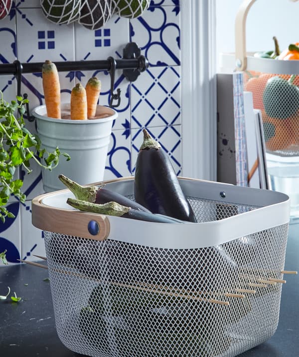 A RISATORP basket, cube-shaped, full of aubergines, and perforated by skewers to create a shelf or partition halfway up.