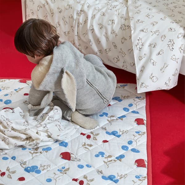 A RÖDHAKE quilted blanket with a rabbit and blueberry pattern on a light-colored background.