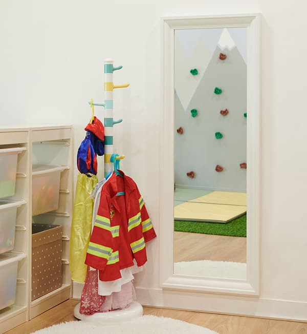 A role play corner with children firefighter costumes hung on a clothing rack.