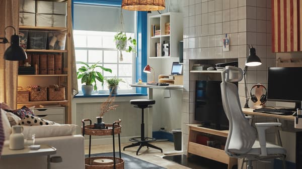 A room at home with a dark gray LIDKULLEN active sit/stand support standing at a TROTTEN sit/stand desk next to a window.