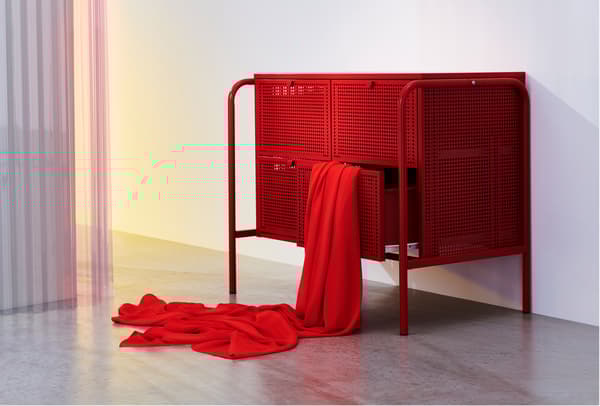 A room with a red NIKKEBY chest of drawers and some red textile hanging from one of the open drawers.