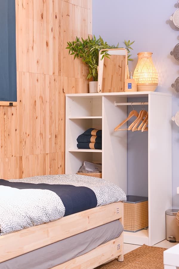 A room with wooden walls featuring a single-sized bed and a cabinet.