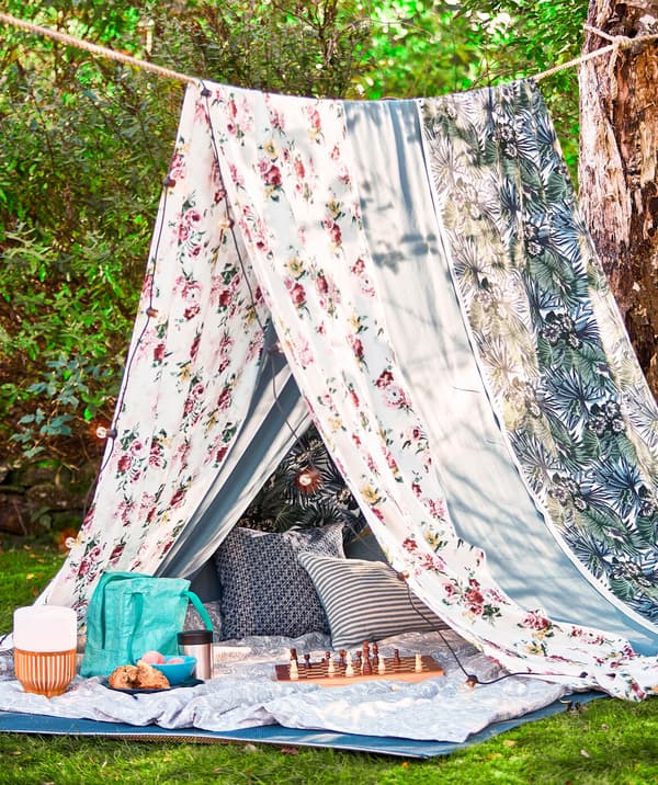 A rope between two trees and two large pieces of fabric hung over the rope to create a summer picnic tent.