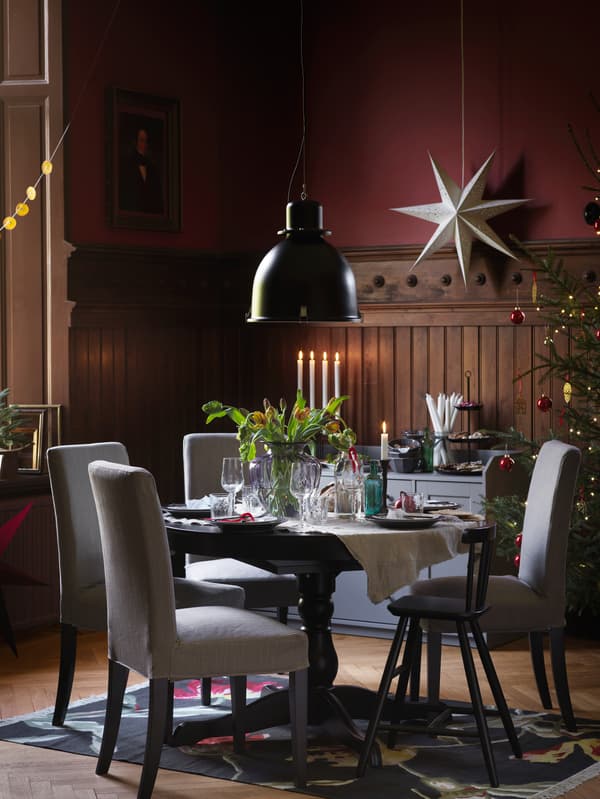 A round black INGATORP table is paired with matching grey chairs and set with an ornate flower display.